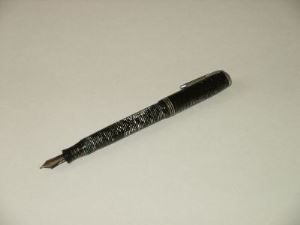DE CAPITULATIE PEN Objectnummer WA 1002. Vulpen, merk Parker, gedateerd ca. 1940. Materiaal schacht: lakhars, pen witgoud. Kleur: zwart-wit gestreept overdwars. Lengte (dichtgeschroefd) 12,8, max. dikte 1,2 cm.